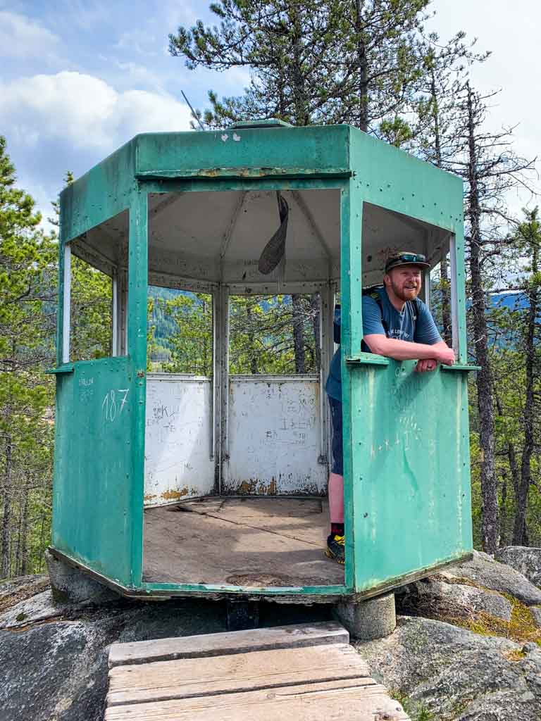 A hiker leans out the window at the old forest fire lookout at Brohm Lake