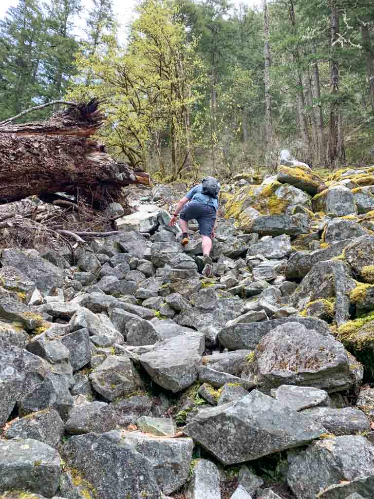 A hiker climbs through a rockslide on the Thompson Trail in Squamish