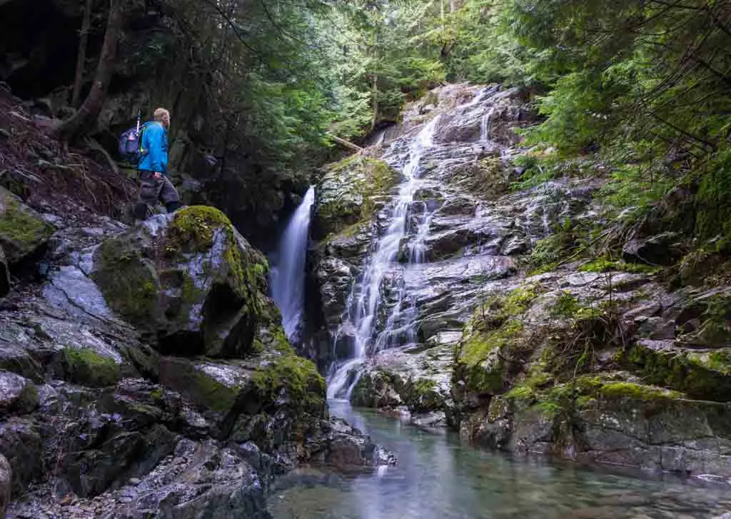 A hiker stands next to Kennedy Falls in North Vancouver, BC