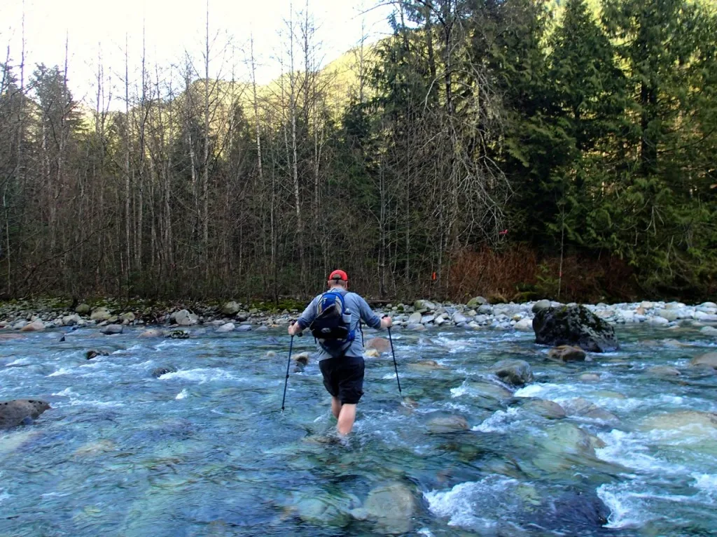 A hiker crossing Lynn Creek on the Big Cedar and Kennedy Falls hike