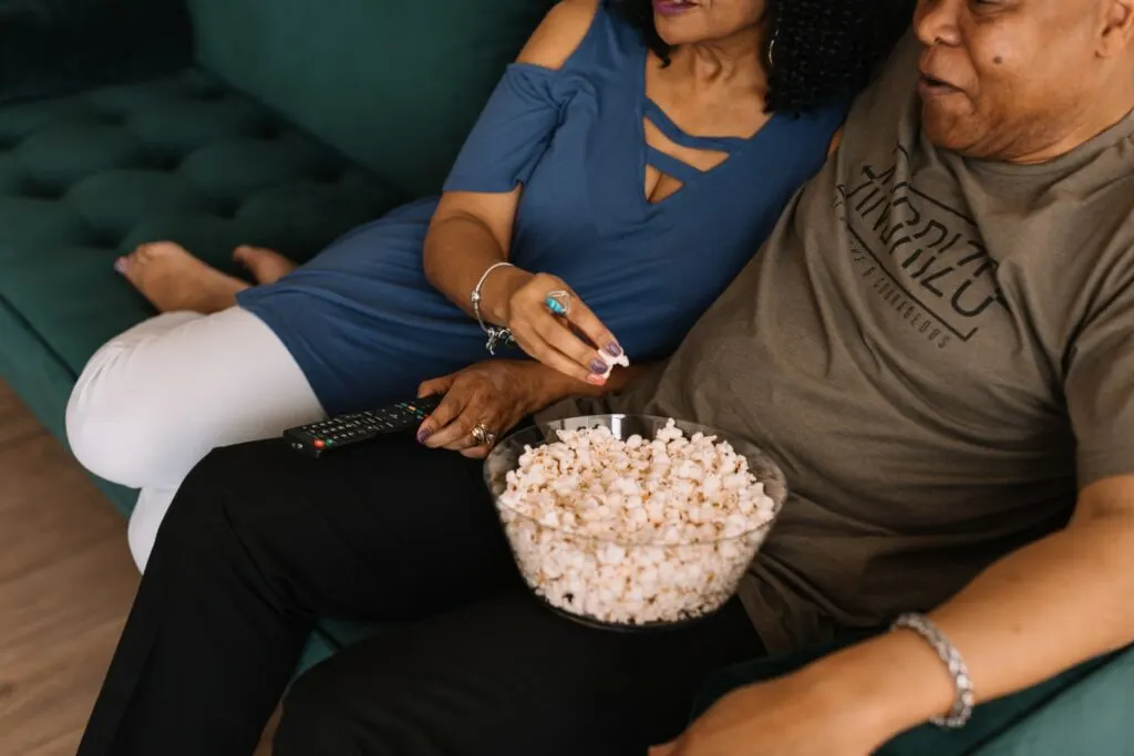 A couple eats popcorn as they watch a movie. A DIY adventure film fest at home is a great Valentine's day idea for outdoorsy couples