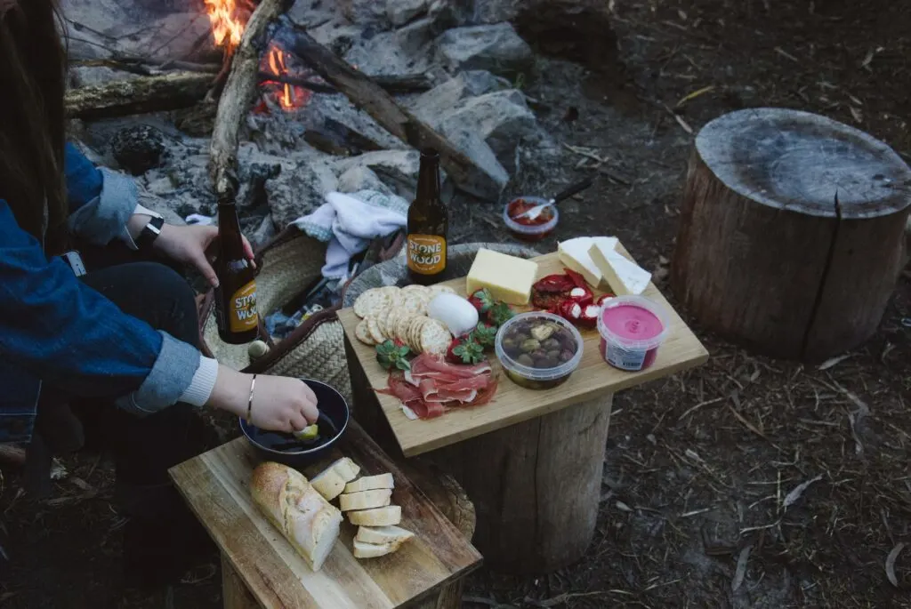 A charcuterie board next to a campfire. One of the best Valentine's ideas for outdoorsy couples: go on a backcountry dinner date