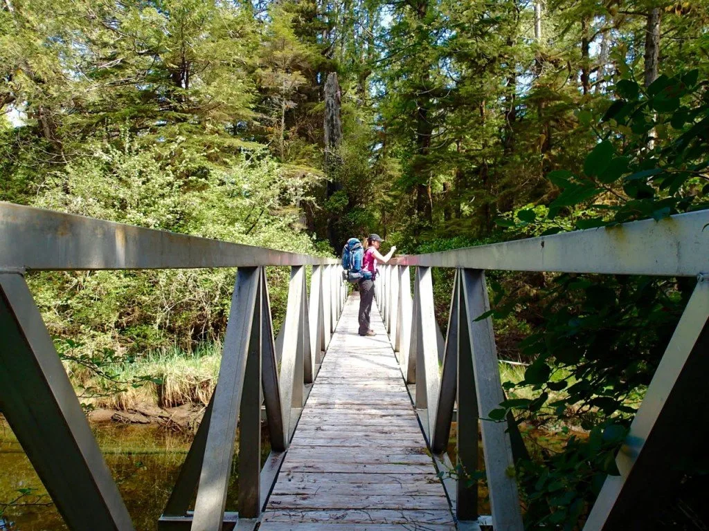 Hikers crossing the bridge over the Kutcous River on the Wild Side Trail near Tofino, BC.