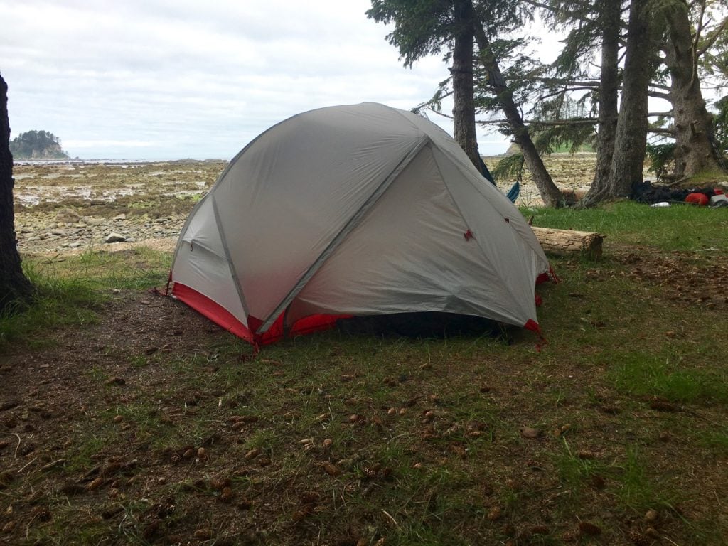 A small tent pitched in front of the shoreline at low tide at Cape Alava on the Ozette Loop