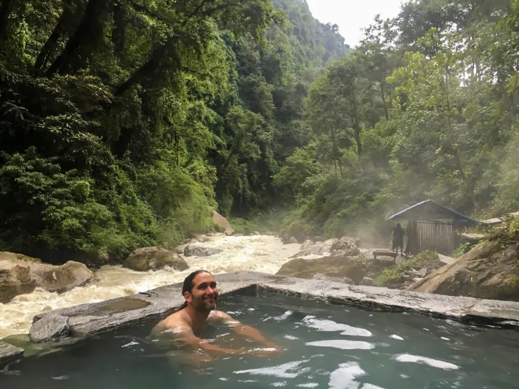 A trekker relaxes in the hot spring at Jhinu Danda on the Annapurna Base Camp trek. What to pack for the Annapurna Base Camp Trek in Nepal.