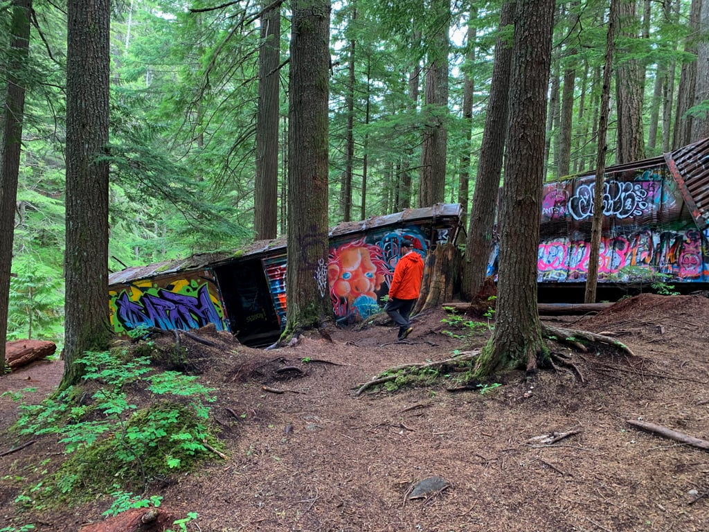 A hiker explores abandoned train cars on the Whistler Train Wreck Trail