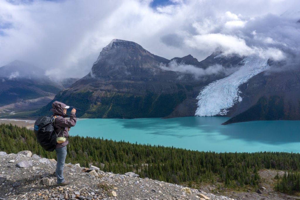 A hiker enjoying the view of glaciers at Berg Lake in Mount Robson Provincial Park