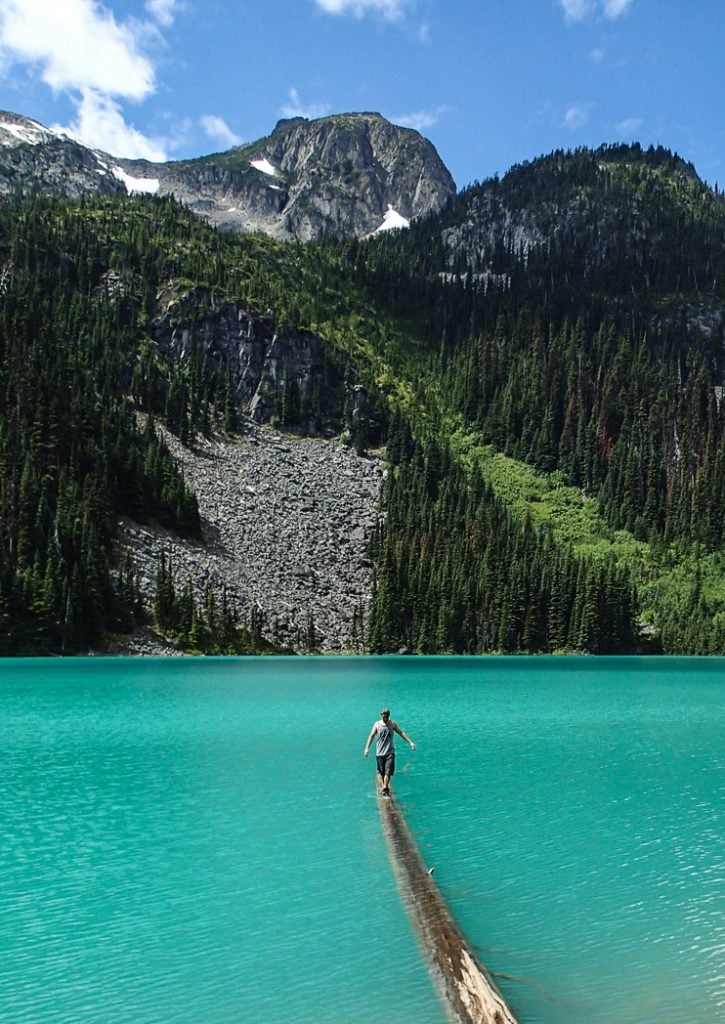 Ein Wanderer balanciert auf einem Baumstamm bei Joffre Lakes in der Nähe von Vancouver