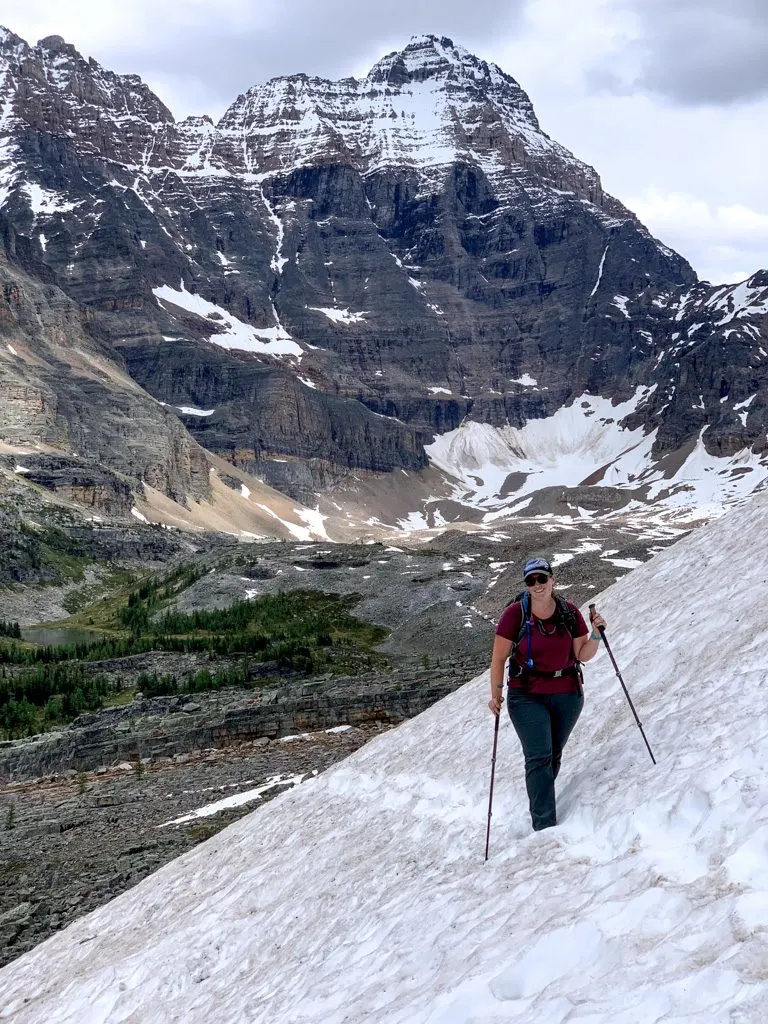 A hiker crossing snow on the All Soul's Alpine Route at Lake O'Hara in Yoho National Park