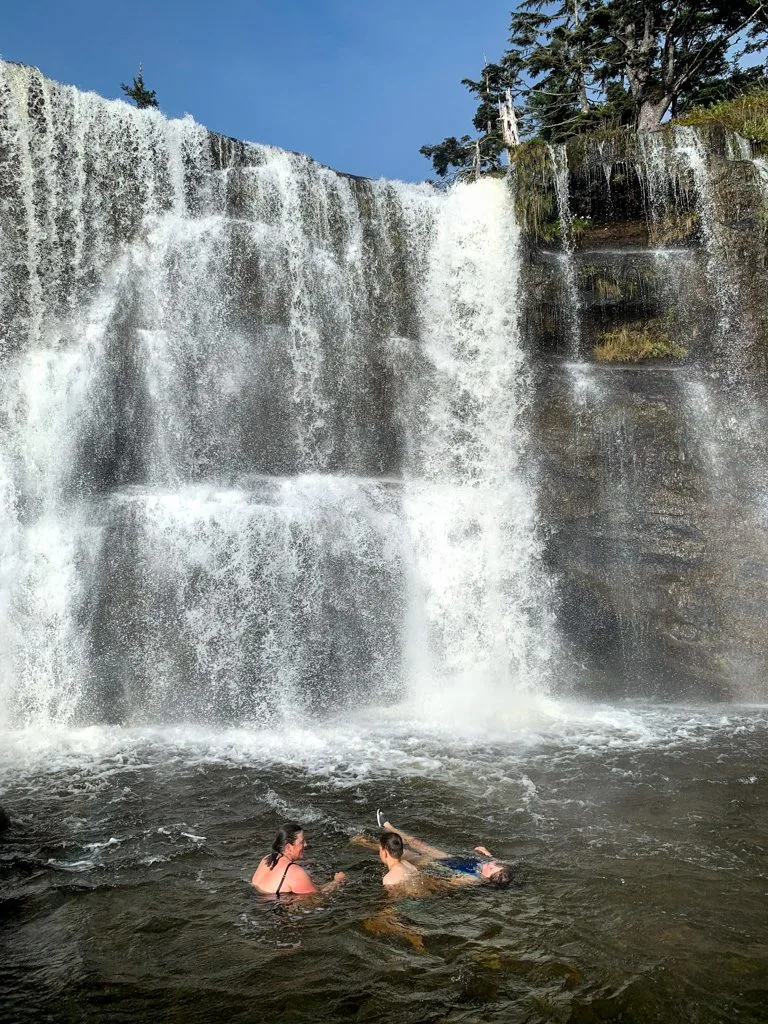 Hikers swimming at Tsusiat Falls on the West Coast Trail