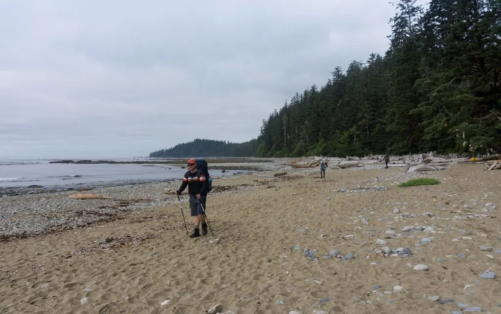 Hikers walking on a sandy beach near Darling River on the West Coast Trail