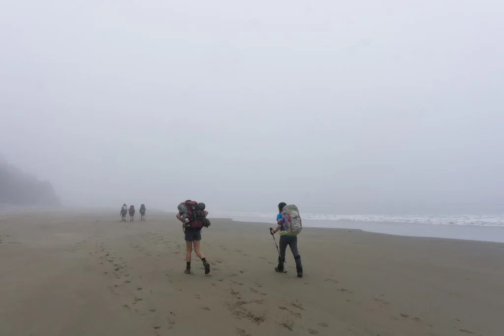 Hikers walk through fog on the beach on the West Coast Trail