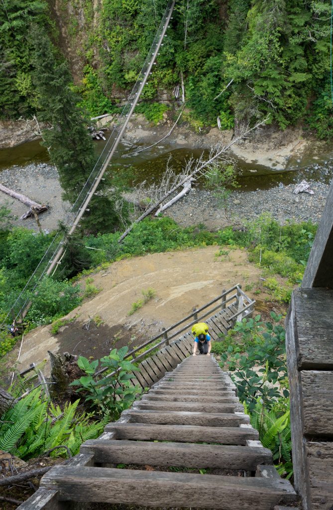Hikers cross the Logan Creek suspension bridge and climb ladders on the West Coast Trail