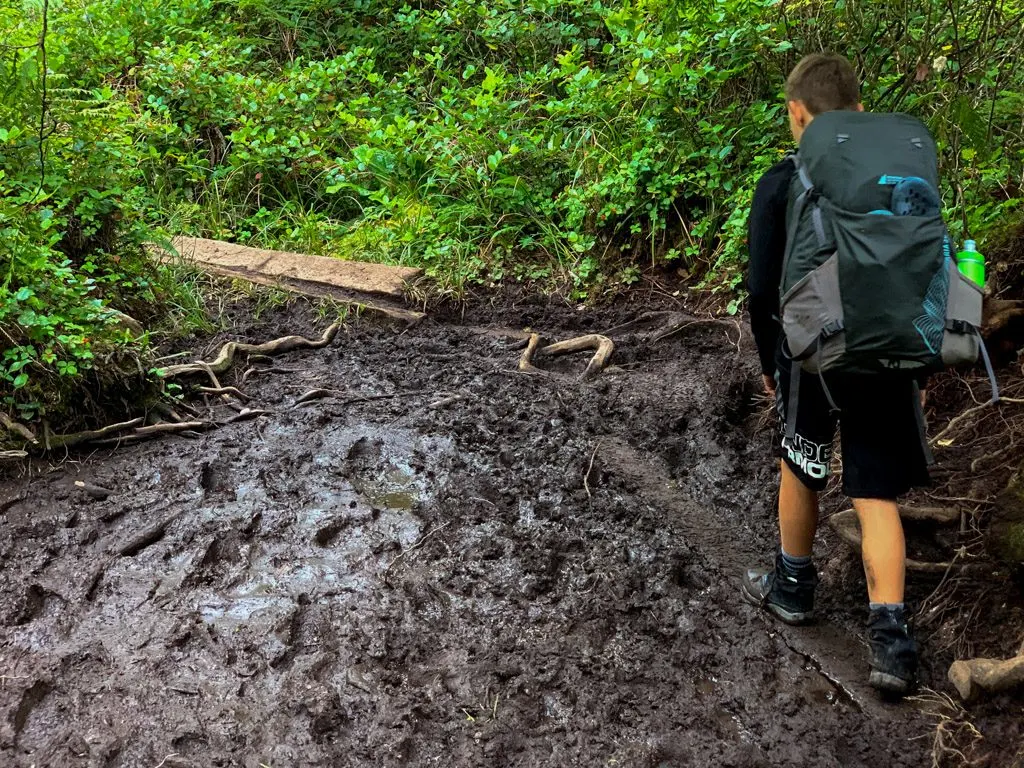 A hiker navigates through a mud bog on the West Coast Trail