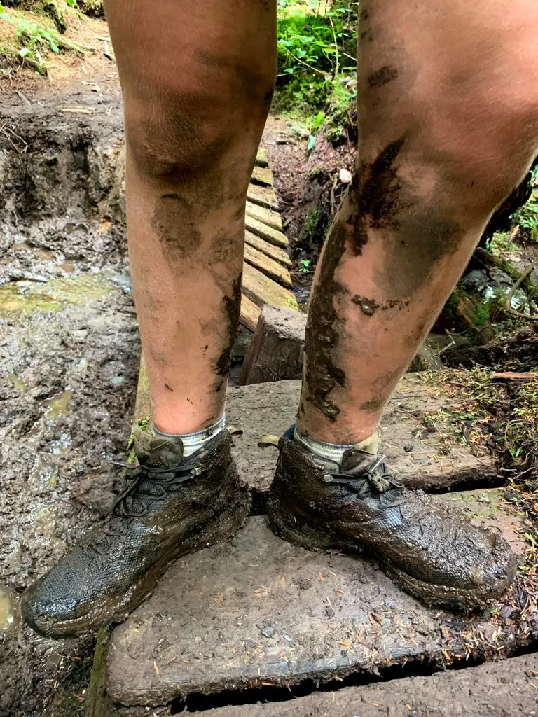 A hikers legs covered in mud on the West Coast Trail