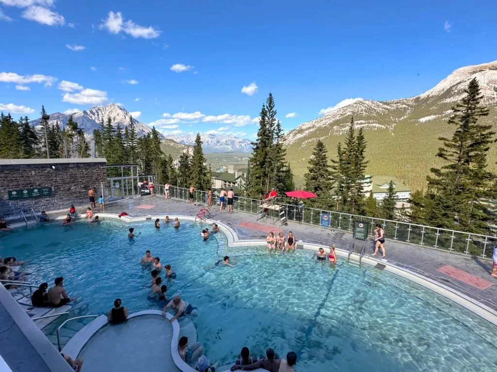 Swimmers at Banff Upper Hot Springs with mountains in the background. 