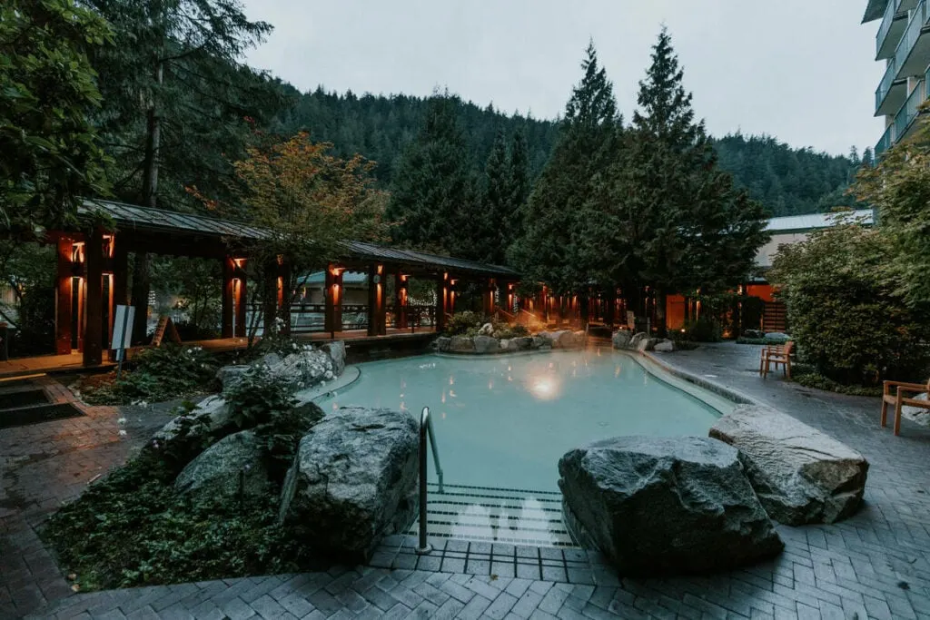 The pools at Harrison Hot Springs at dusk with lights illuminating the area.