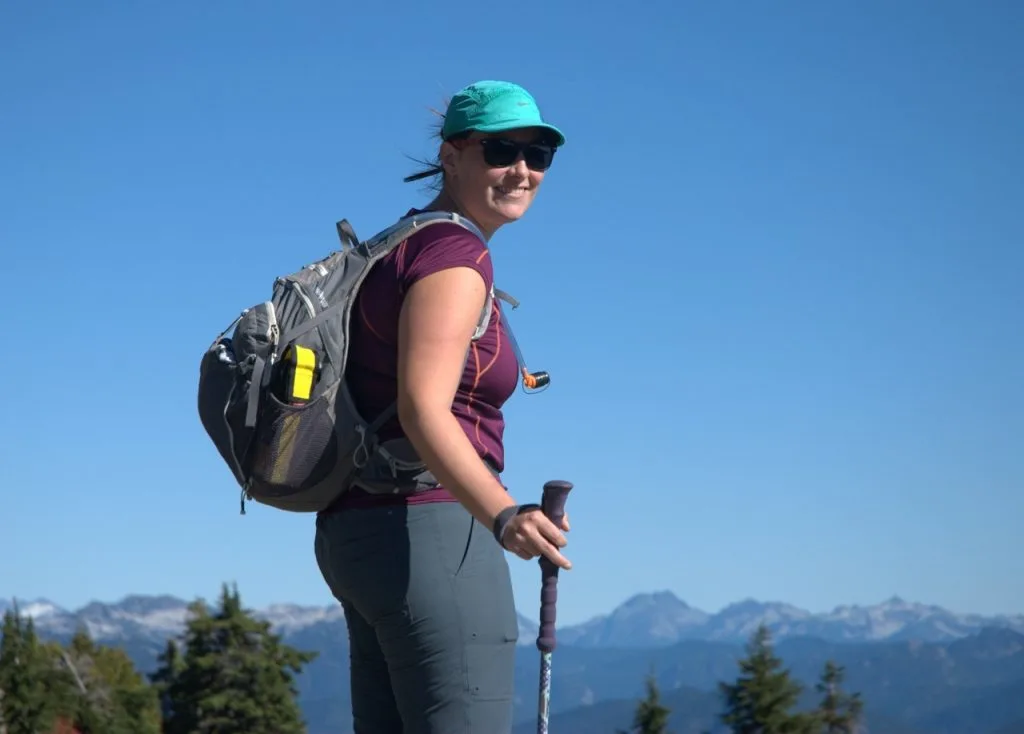 Young person hiking female sitting on top rock, Backpack woman