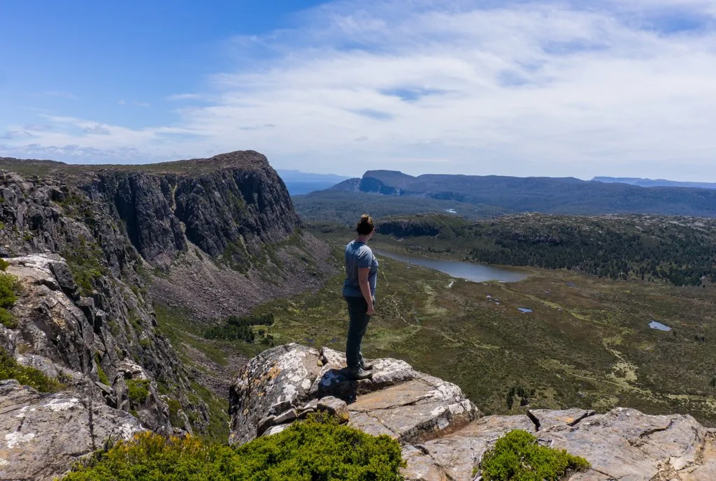 A hiker stands at the peak of Solomon's Throne in Tasmania's highlands