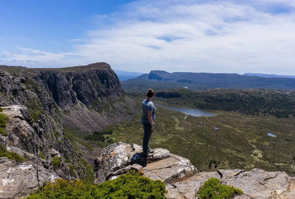 A hiker stands on a rocky outcrop in Walls of Jerusalem National Park