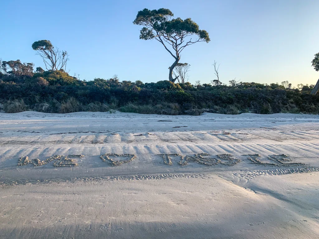 Letters in the sand at Jetty Beach spell out "We love Tassie"