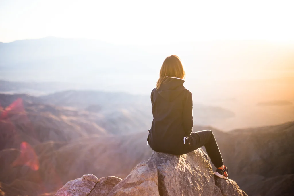 A woman sitting on the peak of a mountain