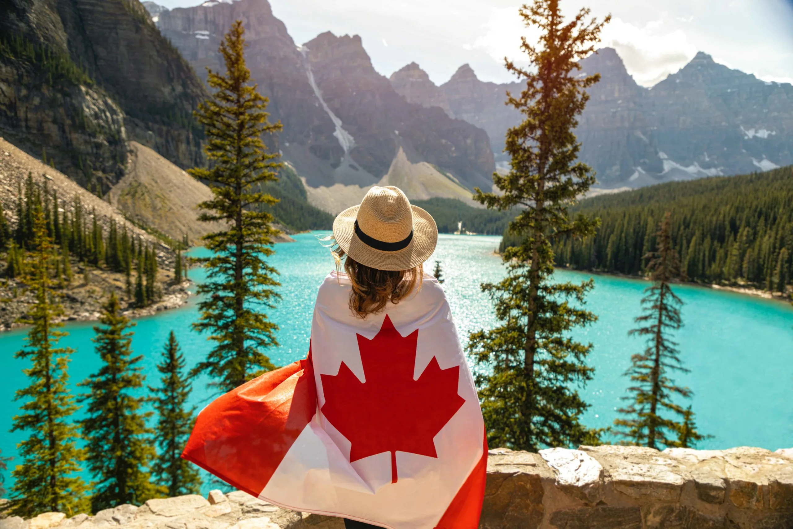 Woman Draped in the Canadian Flag near lake and mountains. The best Canadian adventure books