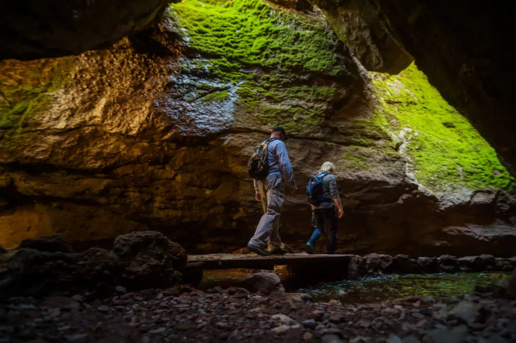 Two hikers walk along a boardwalk into Bear Gulch Cave in Pinnacles National Park in California - it's an under-the-radar US National Park