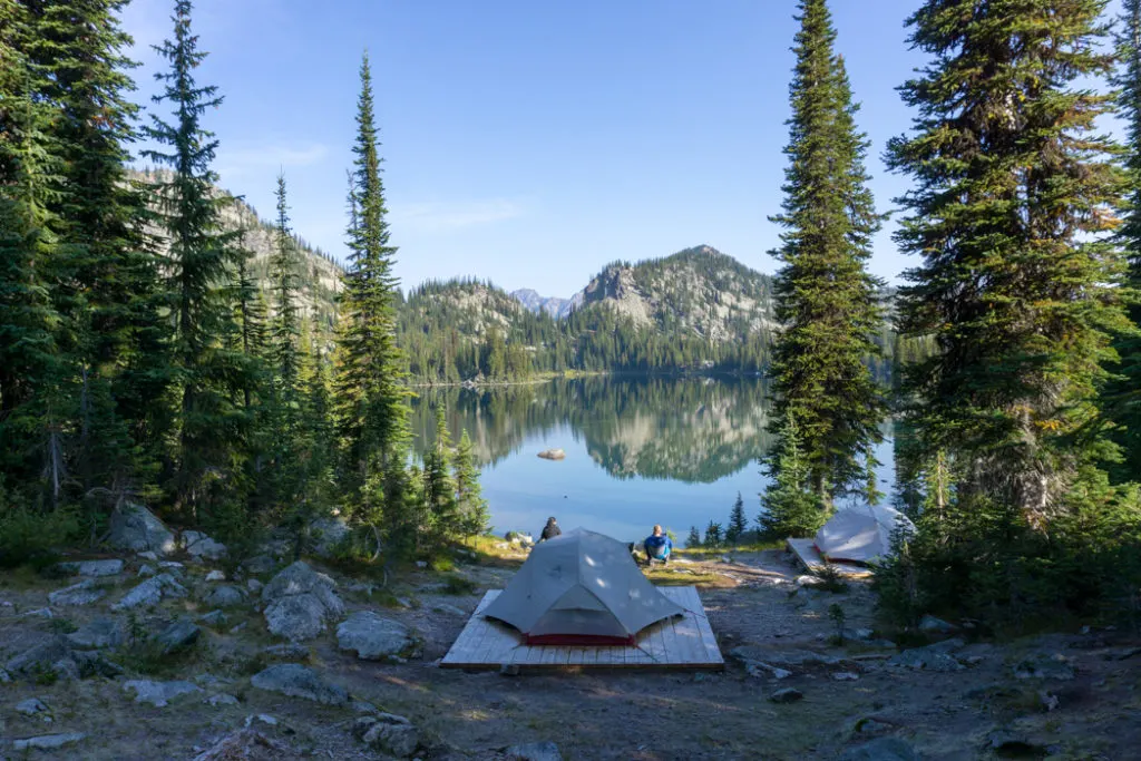 A backpacking tent in front of a still lake at Kokanee Glacier Provincial Park in British Columbia