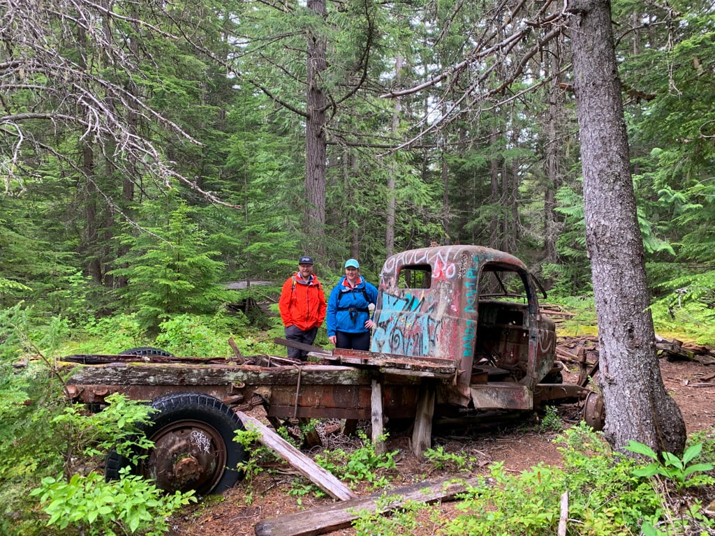 Two hikers next to an abandoned truck near Whistler, BC