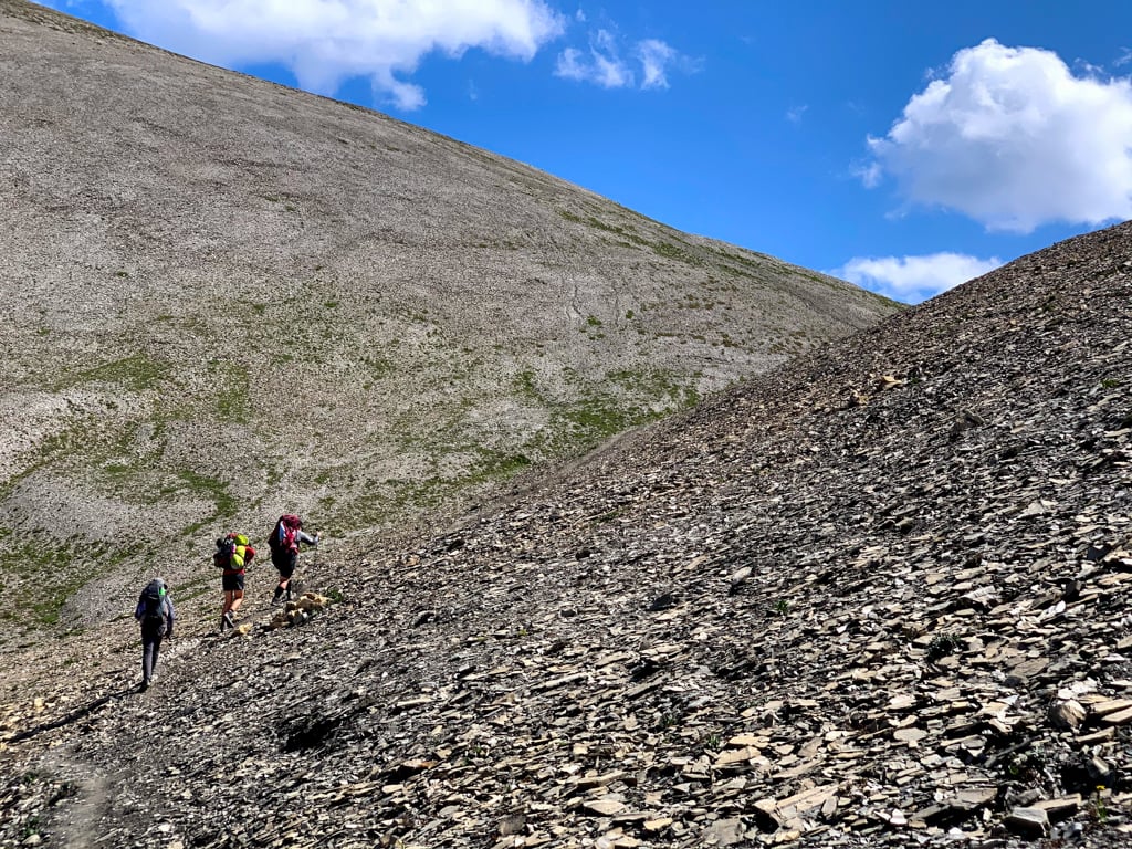 Hikers walking up a scree slope at Numa Pass