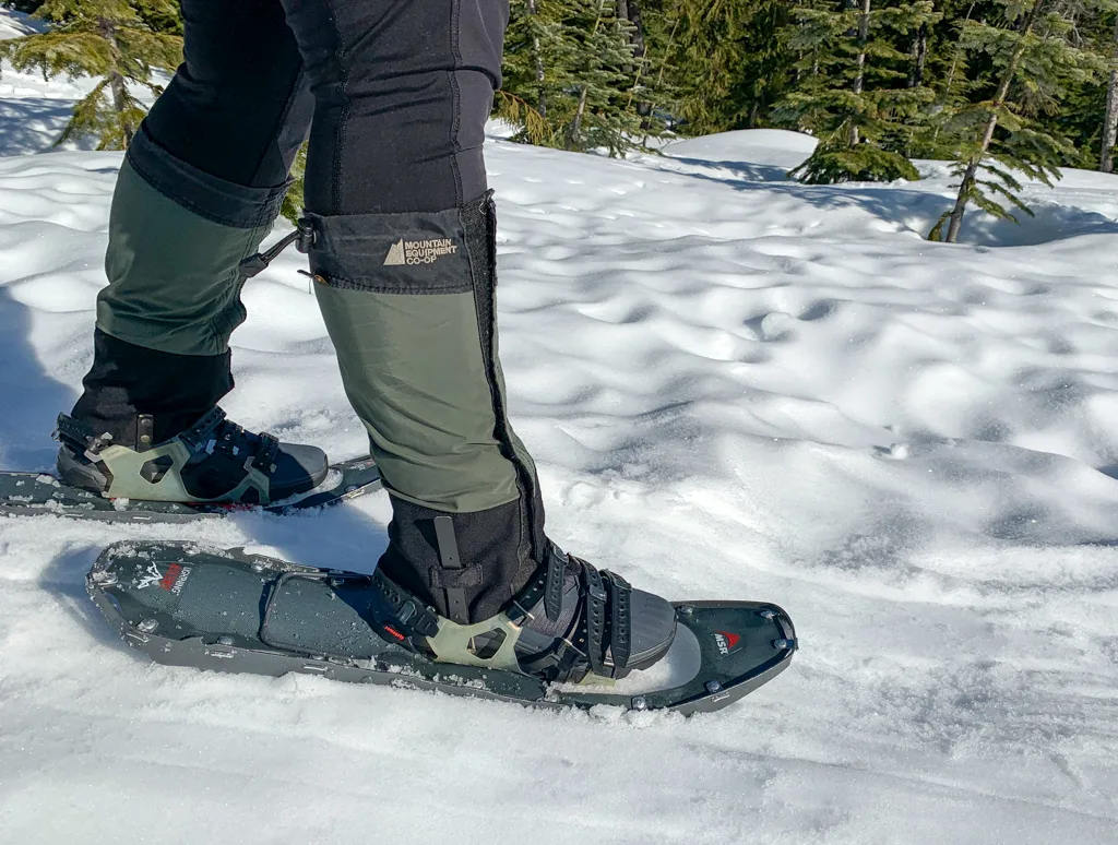 A hiker wears gaiters and snowshoes