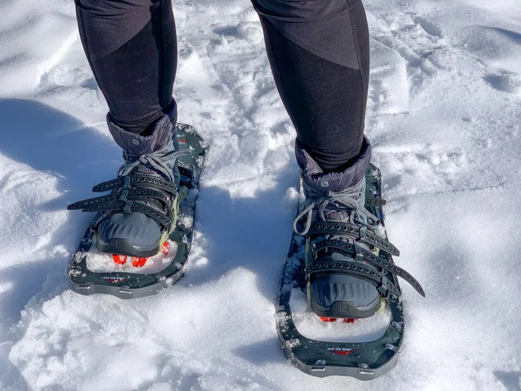 Close up of a a person wearing insulated hiking boots with snowshoes.