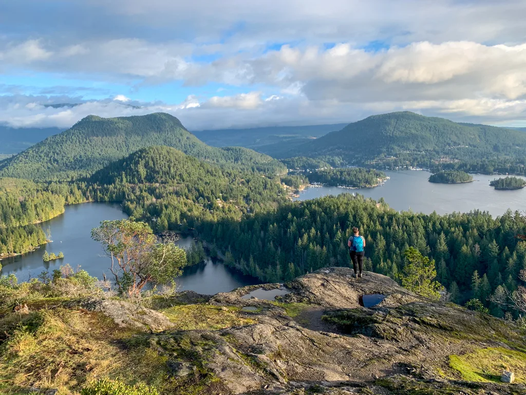 A woman stands on a rocky outcropping on Pender Hill - one of the best hikes on the Sunshine Coast, BC