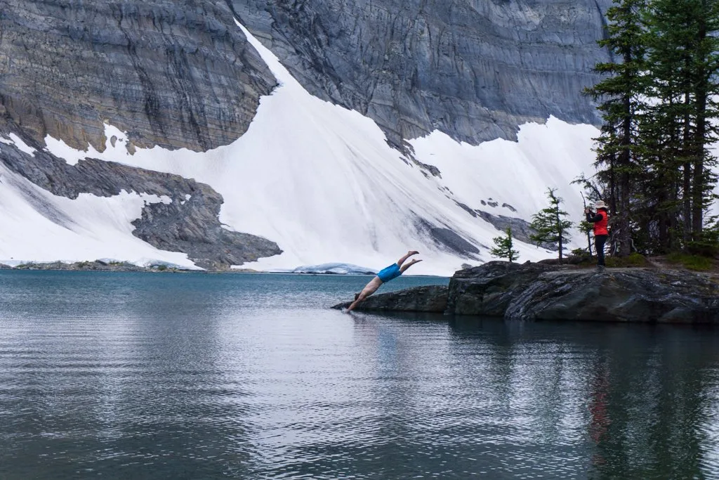 A man dives into Floe Lake on the Rockwall Trail