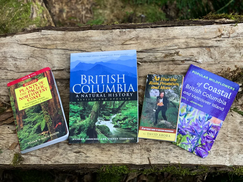 Four British Columbia and Vancouver natural history books spread across a log