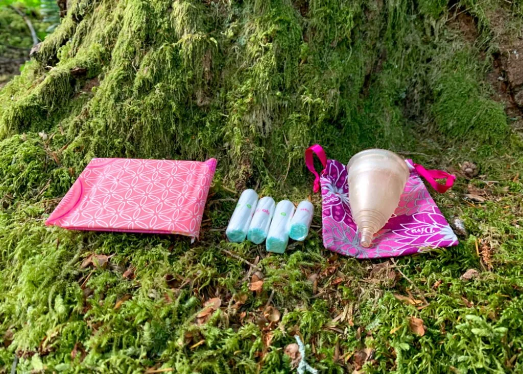 Pads, tampons and a menstrual cup in the forest. Learn how to go hiking with your period.