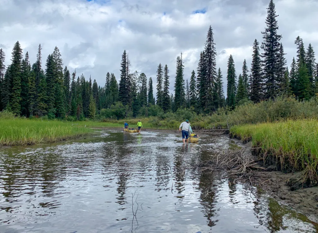 Walking canoes through shallow water in Babcock Creek