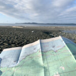 A hiker hold a map on a beach hike - A map is one of the 10 essentials you should bring on every hike.