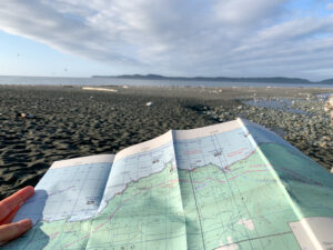 A hiker hold a map on a beach hike - A map is one of the 10 essentials you should bring on every hike.