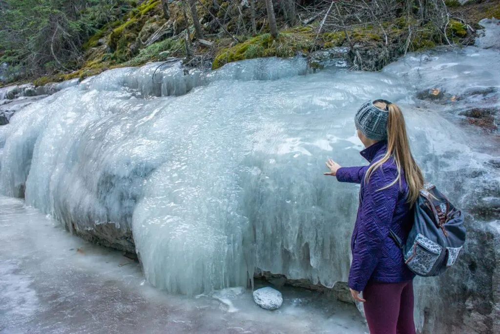 A woman next to an ice flow in Grotto Canyon in Canmore, Alberta