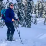 A woman wearing an insulated skirt snowshoes through a snowy forest