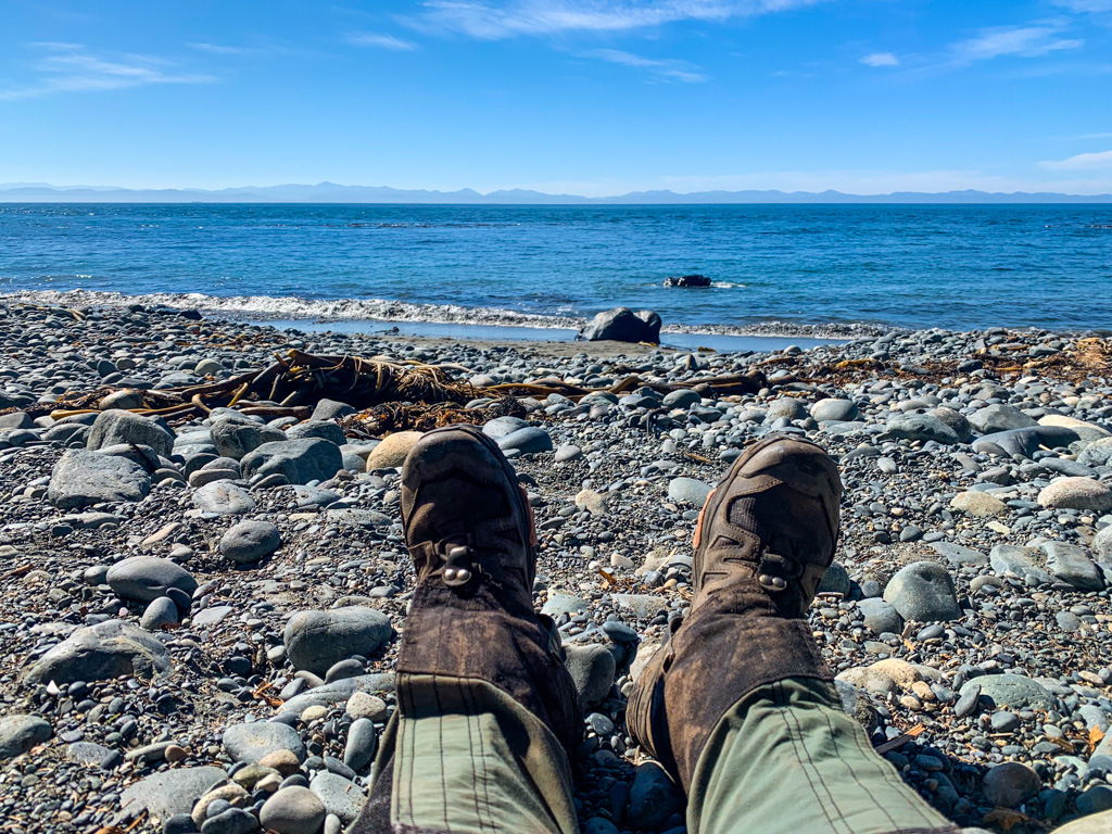 A hiker puts their feet up on the rocks of Mystic Beach