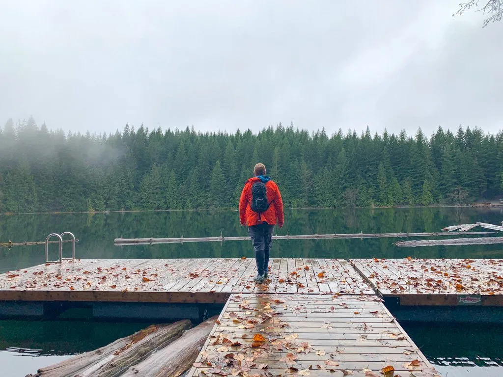 A hiker stands on the dock at Cat Lake on a misty fall day.
