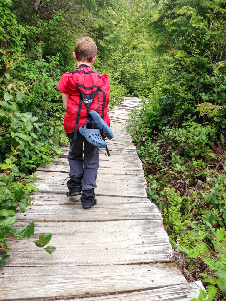 A kid on a backpacking trip walks on a boardwalk in Olympic National Park