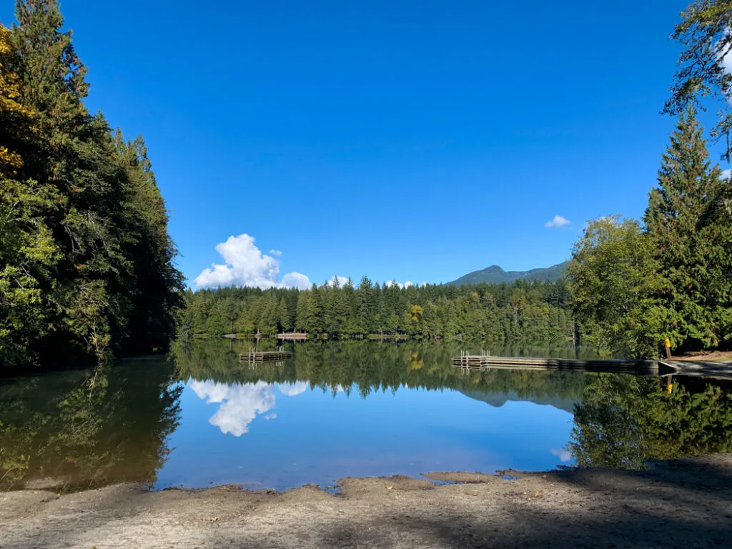 The forest and swimming dock reflected in the still waters of Alice Lake in Squamish. 