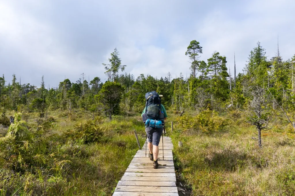 A backpacker walks on a board. Need hiking term definitions? Use this hiking glossary.