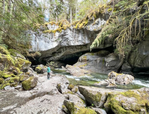A hiker stands at the entrance of Little Huson Cave on Northern Vancouver Island. This guide to Little Huson Guide has driving directions and hiking info to plan your visit.