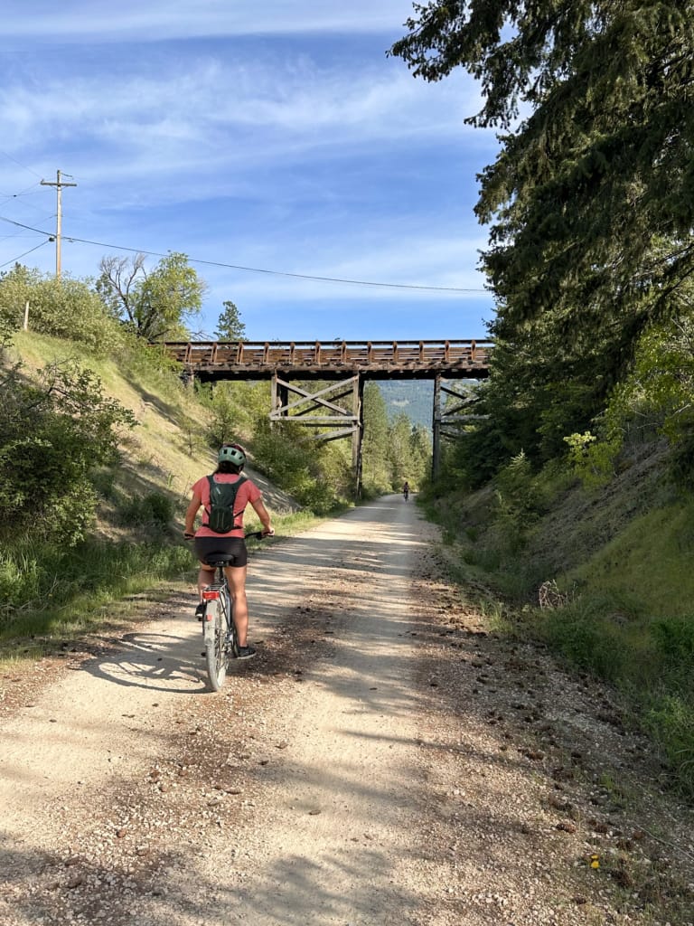Biking under an old trestle on the Okanagan Rail Trail in Vernon