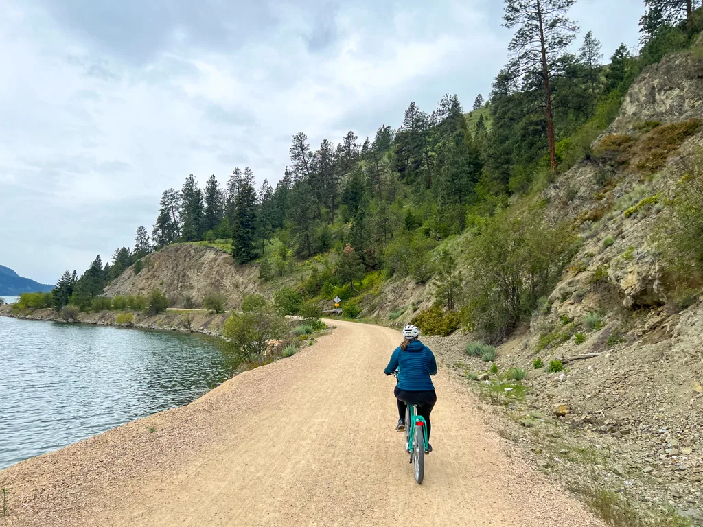 A woman bikes along the Okanagan Rail Trail next to Kalamalka Lake in Vernon, BC